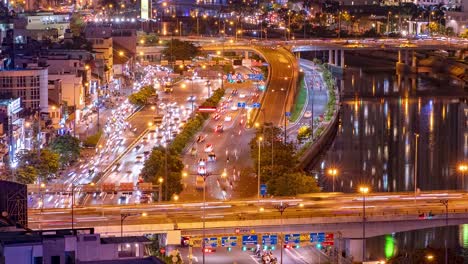 Night-High-Wide-shot-of-busy-motorway-lanes-with-heavy-traffic-passing-by-the-Saigon-river,-Vietnam,-Ho-Chi-Minh-City