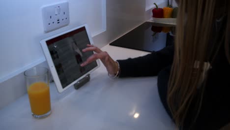Weibliches-Modell-Mit-Einem-Tablet,-Einem-IPod-Auf-Einer-Küchenarbeitsplatte-In-Einer-Modernen-Küche