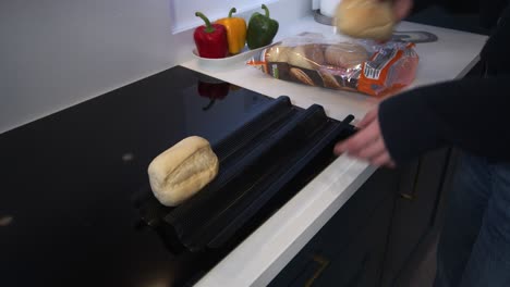 female-model-putting-part-baked-rolls-on-a-baking-tray-in-a-modern-kitchen