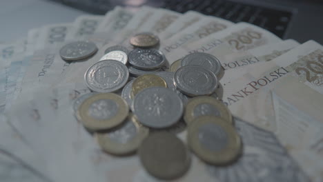 Close-up-shot-of-falling-polish-zloty-coins-falling-on-many-banknotes---Cash-Zloty-of-Poland