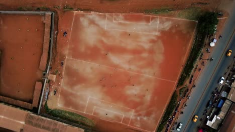 Aerial-view-above-people-soccer-in-middle-of-a-African-city---top-down,-drone-shot