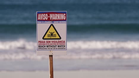 Beach-without-watch-warning-sign,-ocean-or-sea-waves-in-background,-Portugal-signboard