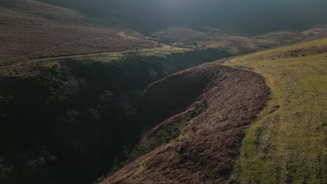 Flying-over-gorge-with-hikers-and-reveal-of-misty-mountain-and-natural-lens-flare-in-English-Lake-District-UK