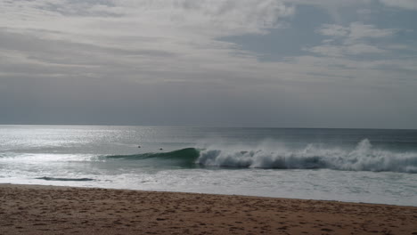 Sandstrand-In-Nazare,-Portugal,-Wellen-Und-Wenige-Surfer,-Statische-Nachmittagsansicht-Des-Atlantischen-Ozeans