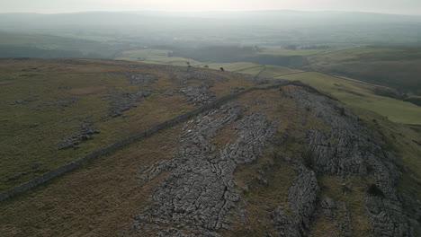 Flying-over-hillside-and-limestone-pavement-revealing-green-patchwork-fields-at-Ingleton-Yorkshire-UK