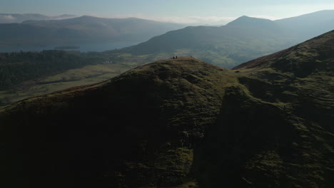 Hikers-on-distant-hillside-with-slow-reveal-of-valley-beyond-in-English-Lake-District-UK