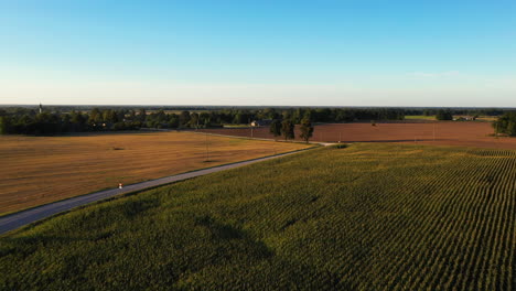 Rural-country-road-and-endless-farmland-fields,-aerial-drone-view