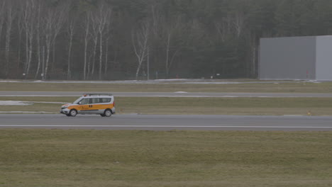 Tracking-shot-of-yellow-airport-service-car-driving-on-runway-of-Gdansk-Airport