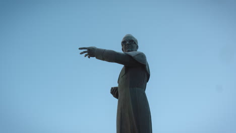 Tiefperspektive-Kameraaufnahme-Einer-Statue-Eines-Priesters,-Der-In-Eine-Richtung-Zeigt
