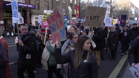In-slow-motion-supporters-join-striking-National-Health-Service-staff-and-march-holding-cardboard-placards-on-a-protest-for-increased-pay-and-better-working-conditions