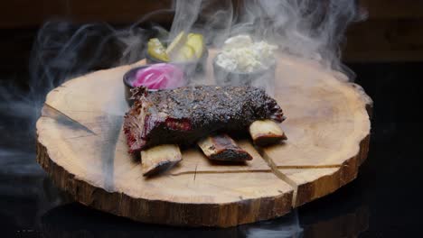 Perfectly-grilled-hot-bbq-ribs-on-a-rustic-wooden-plate-with-pickles-and-a-cloud-of-a-smoke-medium-tilt-up-shot
