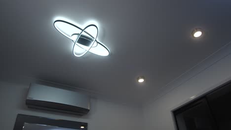 female-model-walking-in-and-turning-on-a-LED-ceiling-light-with-remote-control-and-walking-out