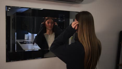 female-model-looking-at-herself,-reflection-and-sorting-out-her-hair-in-a-mirror