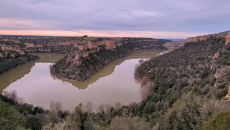 right-to-left-panning-hoces-del-duraton-horseshoe-bend-in-Segovia,-Spain-during-winter-cloudy-sunset