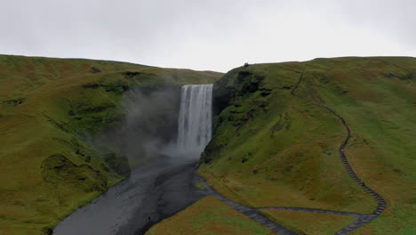 Aerial:-Slow-orbit-shot-of-Skogafoss-waterfall-in-Iceland-on-an-overcast-day