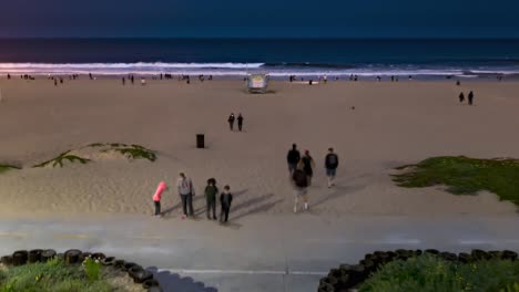 People-Walking-At-The-Strand-Of-Beach-At-Night-With-Wavy-Ocean