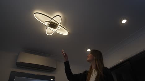 female-model-walking-in-changing-colour-temperature-of-LED-ceiling-lights-with-remote-control-from-warm-white-to-cool-white-and-then-walking-out