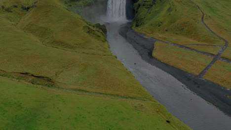 Aerial:-Reveal-shot-of-Skogafoss-waterfall-in-Iceland-on-a-cloudy-day