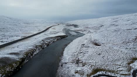 River-by-Road-in-Desolate-Tundra-Landscape-of-Iceland-during-Winter,-Aerial