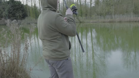 A-fisherman-reeling-a-fishing-rod-at-a-carp-pond