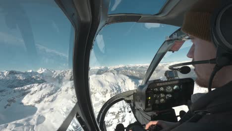 Photographer-in-the-front-seat-of-a-helicopter-ride,-flying-through-the-snowy-mountains-of-Canada,-BC
