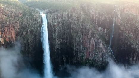 Filmisches-Drohnenvideo-Von-Einem-Hohen-Wasserfall,-Der-Tief-Wasser-Auf-Klippen-Im-Hochgebirge-Australiens-Fallen-Lässt