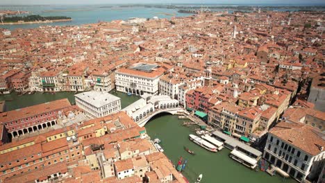 Rialto-Bridge-in-Venice,-Italy,-Aerial-View-Above-Grand-Canal,-City,-Gondolas-and-Boats-Sailing-in-the-Summer-European-Destination-at-Adriatic-Sea