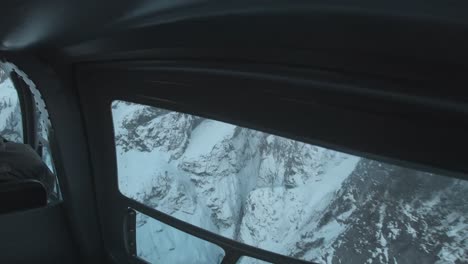 Back-seat-of-a-helicopter-looking-at-the-pilot-flying-through-a-mountain-range