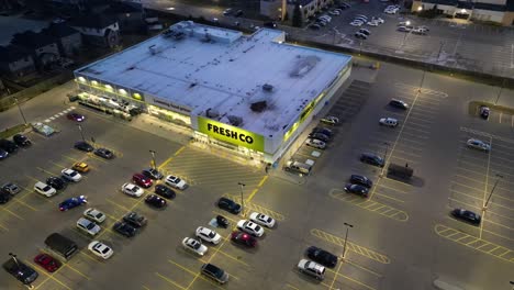 Aerial-Orbit-Shot-of-Freshco-grocery-store-at-night-in-Niagara-Falls,-exterior