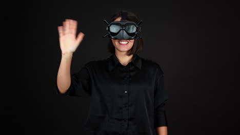 Young-Woman-Wearing-VR-Goggles-Headset-and-Waving-to-Camera,-Slow-Motion,-Black-Background
