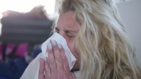 Close-up-of-a-sick-woman-sneezing-multiple-times-into-a-tissue