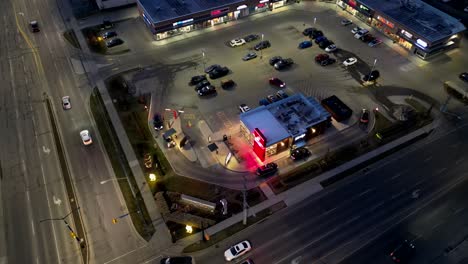 Aerial-Orbit-Shot-of-Wendy's-Drive-Thru-at-Night-lit-by-street-lights-and-cars
