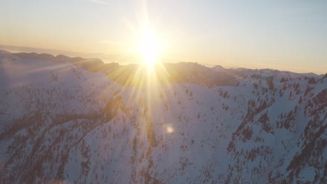 Flying-through-a-cold-snowy-mountain-side-of-Canada,-BC-at-sunset