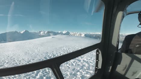 Wide-angle-backseat-footage-of-a-helicopter-landing-on-top-of-a-cold-snowy-winter-mountain-peak-in-Canada,-BC