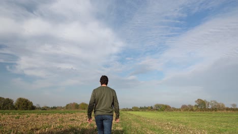 A-young-man-walking-into-a-field-in-a-sunny-day