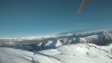 Wide-angle-footage-of-a-helicopter-landing-on-a-snowy-mountain-in-Canada-BC,-with-clear-skies-close-to-sunset