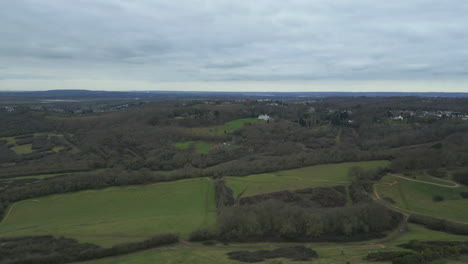Cloudy-view-of-village,-Hadleigh-Park-trails-and-the-Benfleet-Downs-horizon,-drone