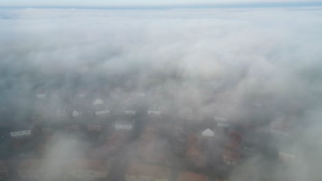Static-drone-footage-of-fast-rolling-fog-with-houses-underneath