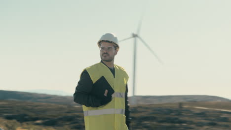 A-renewable-energy-engineer-in-reflective-gear-checks-wind-turbines-while-walking-in-a-field-of-renewable-energy-generators,-emphasizing-the-importance-of-maintenance-for-a-sustainable-energy-future