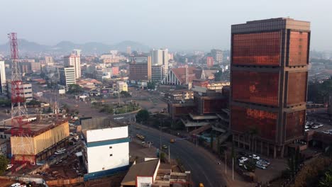 Traffic-in-front-of-the-Block-number-2-building,-Yaounde,-Cameroon---descending,-drone-shot