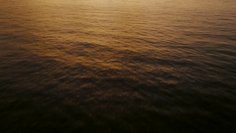 Orange-Sunset,-Sunlight-Over-Calm-Ocean-Wave-Ripples-In-Costa-Rica---aerial-drone-shot