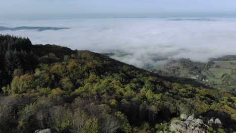 Aerial-drone-view-from-Uchon-Mountain-with-fog-shrouded-rural-landscape-in-background,-Saone-et-Loire-department-in-France