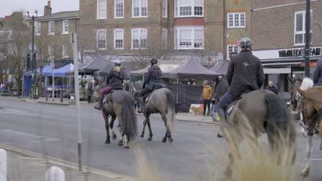 People-riding-on-horses-on-public-street-in-Wimbledon-central-London-on-a-cloudy-day