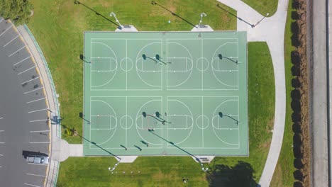 top-down-view-drone-time-lapse-people-exercising-on-a-basketball-court-in-a-southern-California-park-people-move-play-on-a-bright-sunny-day-surrounded-by-lush-greenery-outdoors-joy-of-exercise