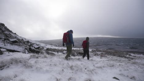 Two-men-hiking-through-open-tundra-and-moorland-towards-a-distant-horizon-in-a-winter-wonderland