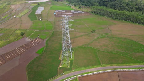 Drone-fly-near-high-voltage-electricity-tower-on-the-middle-of-rice-field