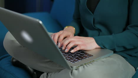 An-unrecongnizable-woman-working-on-a-laptop-while-sitting-cross-legged-on-a-sofa