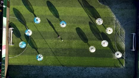 Aerial-footage-of-Zorb-football-being-played-below-at-sunset