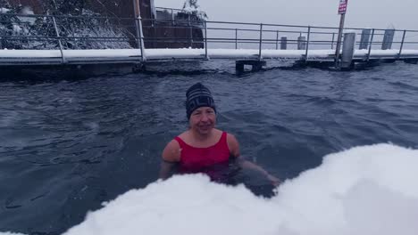 Medium-shot-of-a-woman-taking-an-ice-bath-in-a-Swiss-lake-during-snowfall