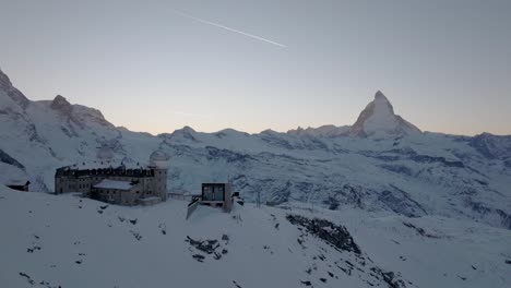 Gornergrat-Obervatory-and-Matterhorn-stunning-mountain-panorama-during-sunset-with-airplane-flying-over-epic-beautiful-Swiss-Alps